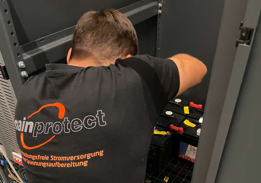 Montage von Batterien in einem USV-Schrank durch einen Techniker von Mainprotect.