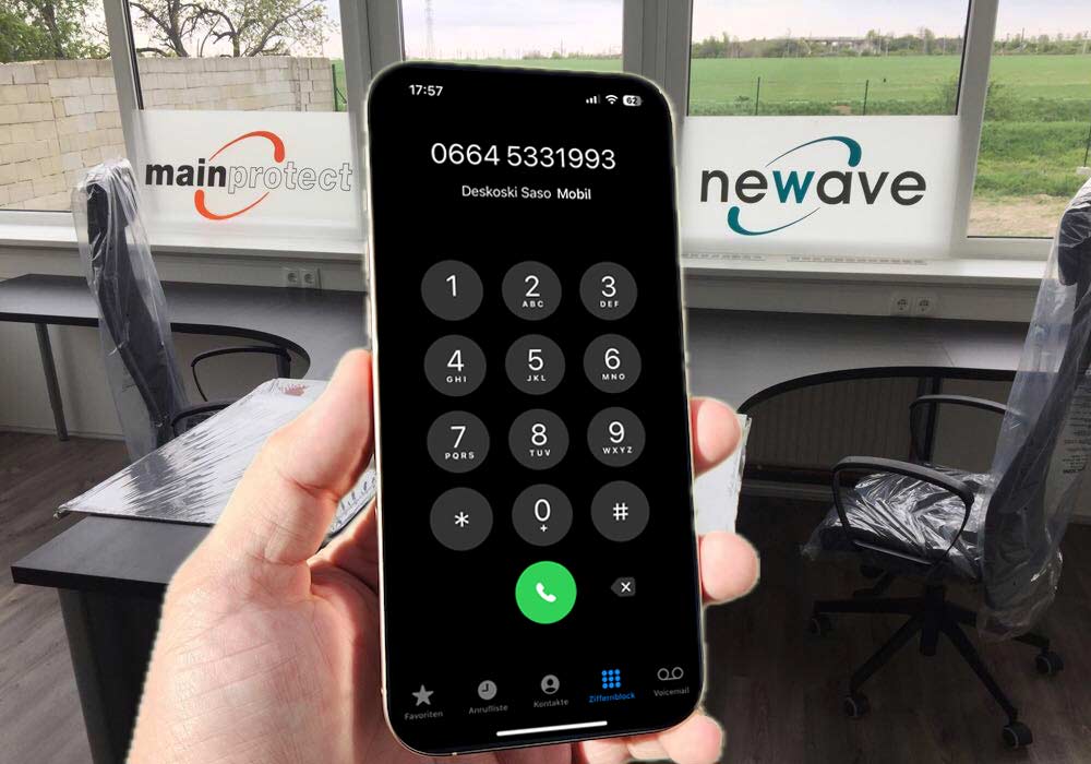 Rufnummer Mainprotect auf einem Mobiltelefon und im Hintergrund das leere Büro mit den Logos von Newave und Mainprotect auf den Fenstern.